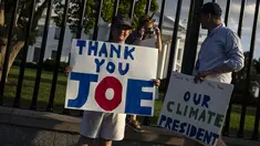 Hugh Kieve (10) memegang papan bertuliskan 'Terima Kasih Joe' bersama saudara perempuannya Margot dan ayahnya David Kieve di sepanjang Pennsylvania Avenue di depan Gedung Putih, Minggu (21/7/2024). (SAMUEL CORUM / AFP)