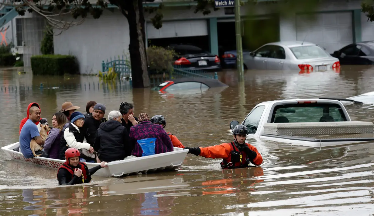 Tim SAR mengevakuasi warga menggunakan perahu karet melintasi banjir di San Jose, California, Selasa (21/2). Banjir terjadi akibat meluapnya Sungai Coyote Creek yang tidak mampu menampung debit air setelah hujan lebat. (AP Photo/Marcio Jose Sanchez)