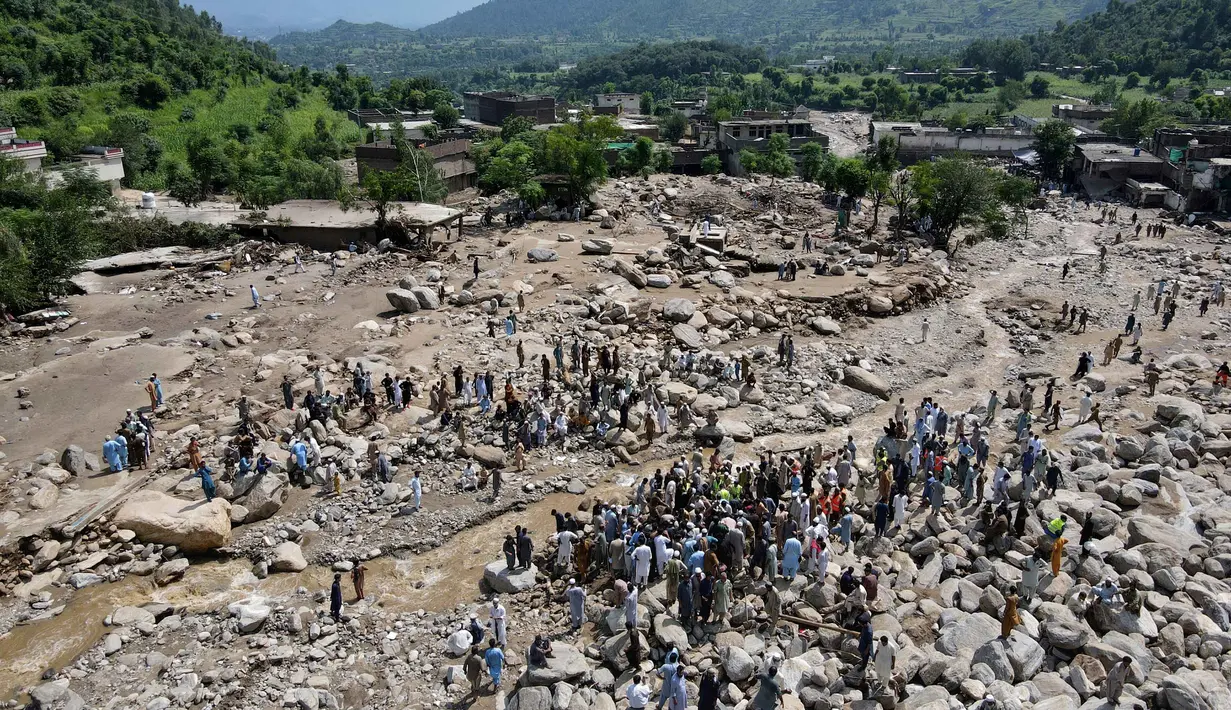 Pemandangan dari udara menunjukkan para korban banjir berkumpul di dekat rumah-rumah yang rusak di sepanjang tepi sungai yang dikelilingi batu-batu besar di distrik Buner, provinsi Khyber Pakhtunkhwa, Pakistan pada 17 Agustus 2025. (Abdul MAJEED/AFP)