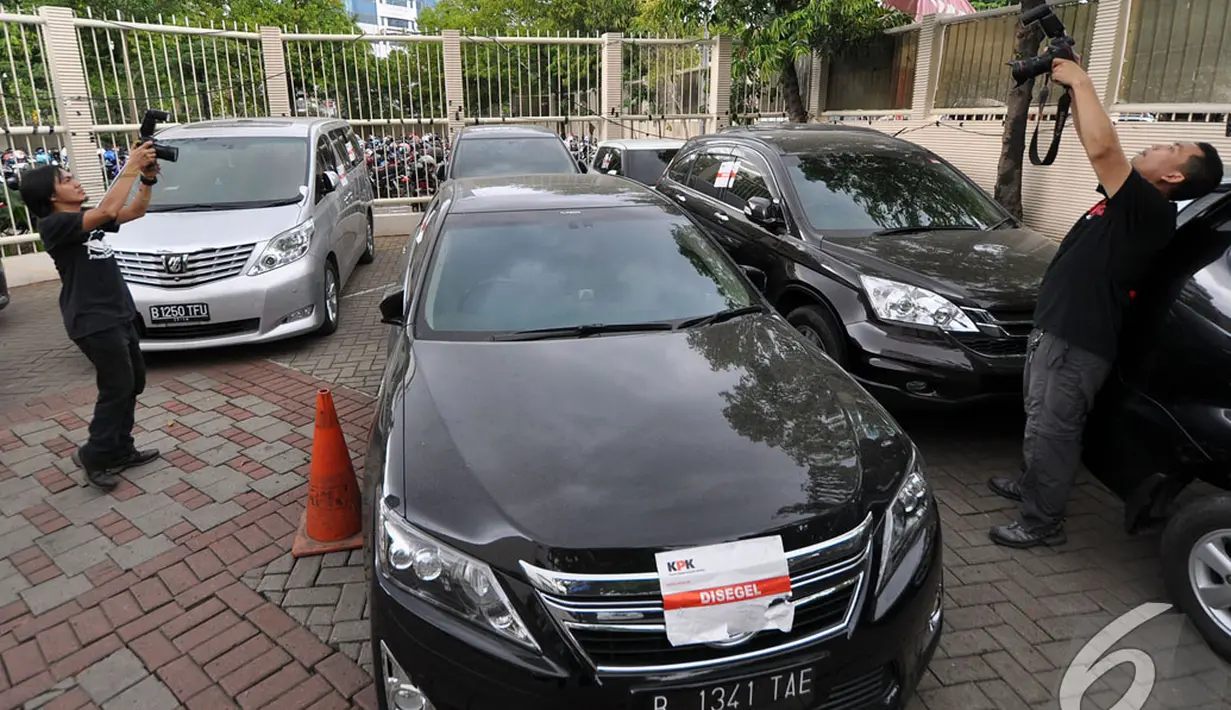 Dua orang wartawan mengabadikan gambar mobil Fuad Amin Imron yang disita KPK, Jakarta, Selasa (23/12/2014). (Liputan6.com/Mihtahul Hayat)