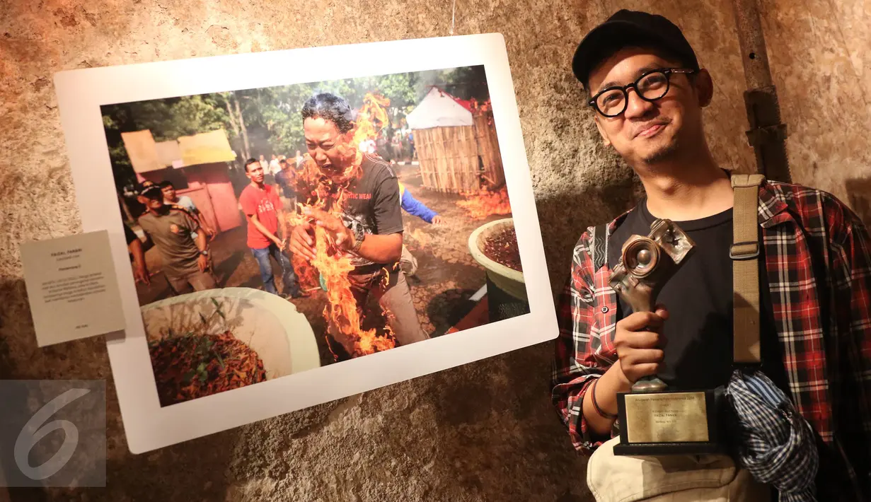 Juara 2 Kategori Spot News pewarta foto Liputan6.com, Faizal Fanani berpose di depan karyanya berjudul " Terbakar Hidup-hidup" sambil memegang trofi Anugerah Pewarta Foto Indonesia (APFI) ke-VI di Bandung, Sabtu (9/4). (Liputan6.com/Immanuel Antonius)