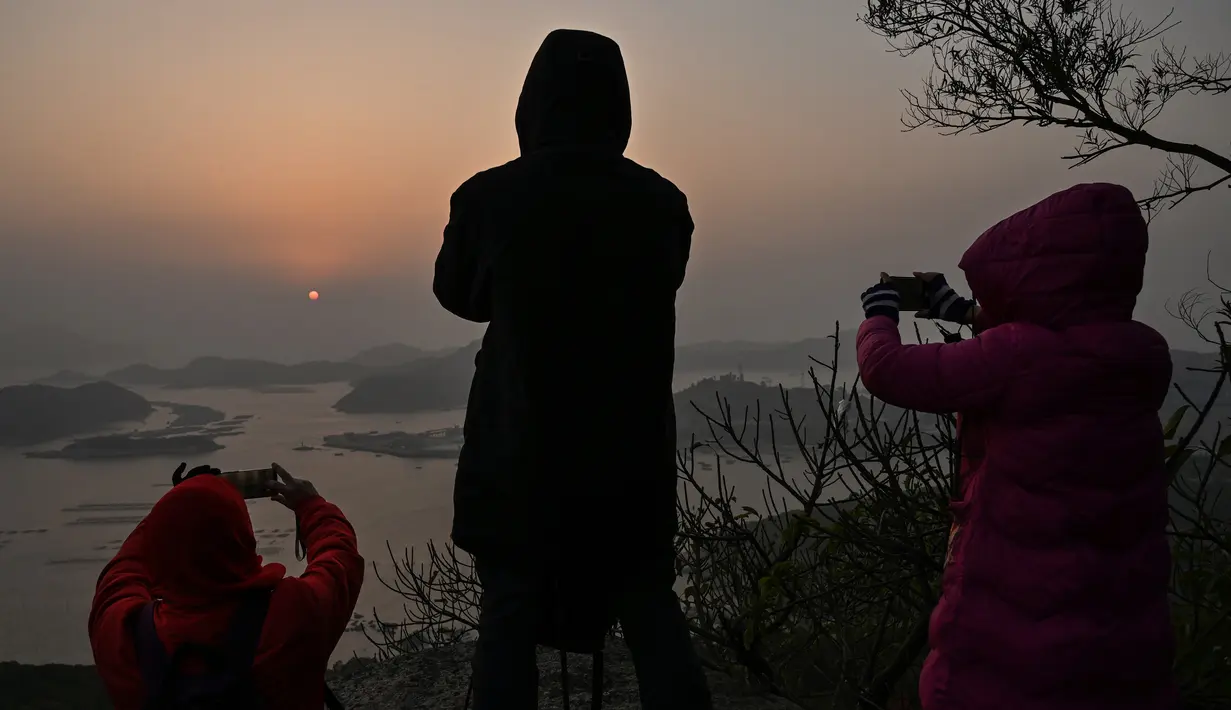 Wisatawan mengambil foto matahari terbit di Desa Hua Zhu, Xiapu, Provinsi Fujian, China, Kamis (12/12/2019). Xiapu menjadi daya tarik tersendiri bagi fotografer pemula karena jauh dari gedung pencakar langit dan hiruk pikuk kota-kota besar di China. (RETAMAL HECTOR/AFP)