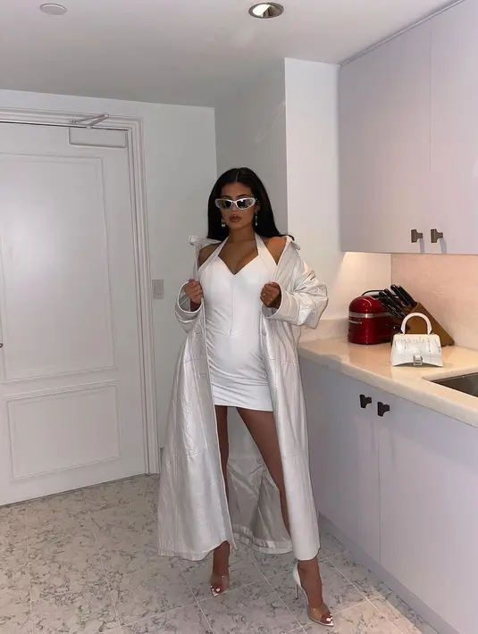 Terakhir, Kylie Jenner tampil dengan baby bump yang sudah mulai nampak dengan outfit serba putih. Mini dress yang ditumpuknya dengan long coat yang juga berwarna putih. Sebagai statement accessories, ia menambahkan sunglasses dan high heels. Foto: Instagram.