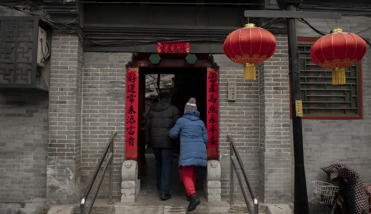 Seorang pria dan wanita berjalan ke halaman rumah mereka di daerah hutong di Beijing (26/2). Hutong-hutong adalah kawasan kejiranan tempat tinggal yang masih membentuk pusat Beijing Lama. (AFP Photo/Nicolas Asfouri)