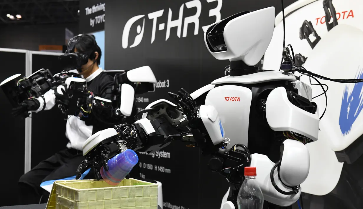 Robot humanoid generasi ketiga T-HR3 mengambil gelas saat Pameran Robot Internasional 2017 di Tokyo (29/11). T-HR3 dikendalikan dari Master Maneuvering System yang memungkinkan seluruh tubuh robot beroperasi. (AFP/Toru Yamanaka)