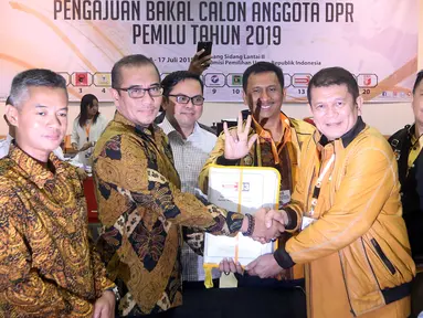 Sekjen Partai Hanura Harry Lontung Siregar (dua kanan) berjabat tangan dengan Komisioner KPU Hasyim Asy'ari (dua kiri) saat menyerahkan berkas pendaftaran bakal calon legislatif di KPU, Jakarta, Selasa (17/7). (Liputan6.com/JohanTallo)