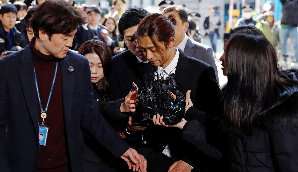 Penyanyi Korea Selatan, Jung Joon Young menjawab pertanyaan wartawan setibanya di Kantor Polisi Metro Seoul, Kamis (14/3). Jung Joon Young dituduh melakukan rekaman  secara ilegal dan membagikannya di media sosial. (REUTERS/Kim Hong-Ji)
