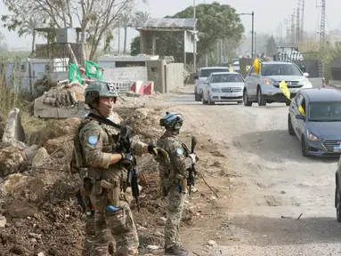 Kontingen Prancis dari Pasukan Sementara Perserikatan Bangsa-Bangsa (PBB) di Lebanon (UNIFIL) berpatroli, sementara warga yang mengungsi sambil mengibarkan bendera Hizbullah kembali ke rumah mereka melalui jalan darurat yang dibangun di lokasi jembatan Qasmieh yang hancur akibat serangan Israel, di wilayah Al-Qasmiyeh, Lebanon Selatan, pada Sabtu 18 April 2026. Israel dan Lebanon resmi menyepakati gencatan senjata selama 10 hari. (MAHMOUD ZAYYAT/AFP)