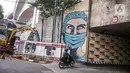 Pengendara motor melintas dekat lukisan mural melawan COVID-19 di Kawasan Cikokol, Cawang, Jakarta, Minggu (4/10/2020).  Mural masih dianggap menjadi sarana edukasi kesehatan yang tepat bagi warga untuk menjaga diri dari penularan virus Covid 19. (Liputan6.com/Faizal Fanani)