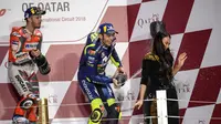 Pembalap Movistar Yamaha, Valentino Rossi saat merayakan podium MotoGP Qatar 2018 bersama Marc Marquez dan Andrea Dovizioso. (KARIM JAAFAR / AFP)