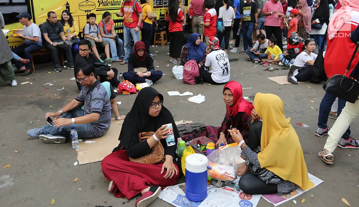 Pengunjung menikmati makan sambil lesehan jelang Closing Ceremony Asian Games 2018 di kawasan Gelora Bung Karno, Jakarta, Minggu (2/9). Kursi yang penuh menyebabkan mereka duduk lesehan. (Liputan6.com/Fery Pradolo)