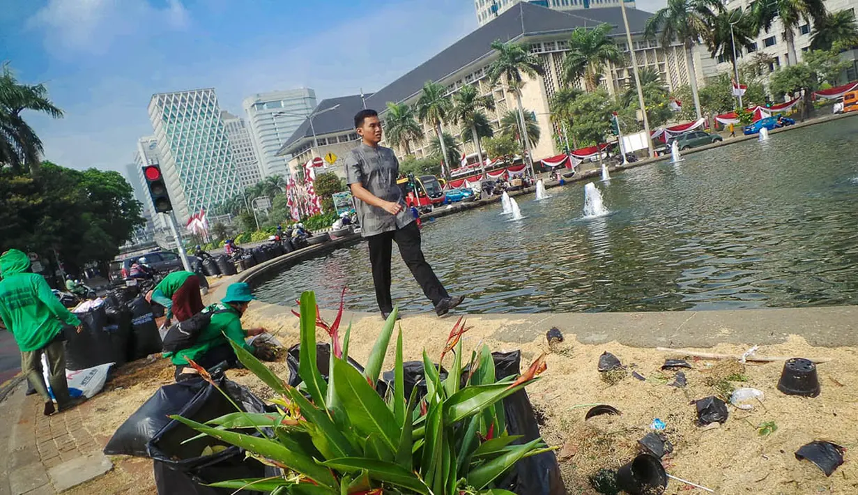 Petugas dinas pertamanan membersihkan Taman Silang Monas yang rusak akibat injakan massa Prabowo, Jakarta, Jumat (22/8/14). (Liputan6.com/Faizal Fanani)