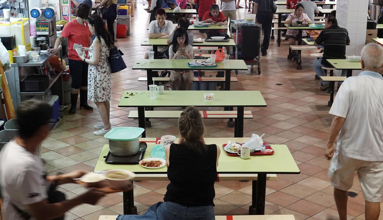 Pusat jajanan menerapkan langkah social distancing atau jaga jarak sosial dengan memasang pita perekat merah di area tempat duduk di wilayah Bugis Singapura pada 28 Maret 2020. Warga di Singapura yang melanggar perintah jaga jarak akan dikenakan denda sekitar Rp 1112 juta. (Xinhua/Then Chih Wey)