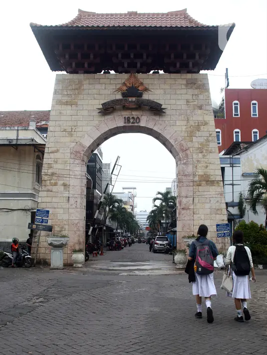 Dua orang pelajar berjalan di depan gerbang kawasan Pasar Baru, Jakarta, Kamis (22/9/2022). Penetapan Kompleks Pasar Baru sebagai Situs Cagar Budaya dikarenakan bangunan pada kawasan ini memiliki struktur cagar budaya yang menyimpan informasi mengenai kegiatan manusia pada masa lalu. (Liputan6.com/Helmi Fithriansyah)