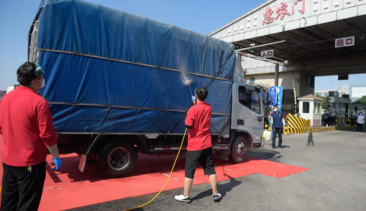 Para staf mendisinfeksi sebuah kendaraan yang akan keluar dari pasar Xinfadi di Distrik Fengtai di Beijing, ibu kota China, pada 7 Juli 2020. Kelompok pertama yang terdiri dari 5.000 orang lebih akan diizinkan pulang dengan tertib, menurut otoritas Distrik Fengtai. (Xinhua/Peng Ziyang)