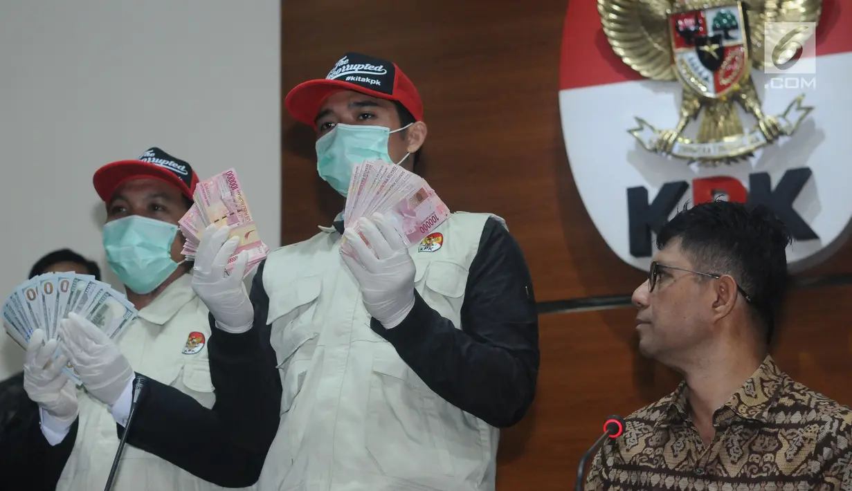 Petugas KPK menunjukkan barang bukti hasil operasi tangkap tangan terhadap Bupati Jombang, Nyono Suharli Wihandoko di Gedung KPK, Jakarta, Minggu (4/2). KPK menyita uang Rp 25,5 Juta dan 9.500 US Dollar. (Liputan6.com/Helmi Fithriansyah)