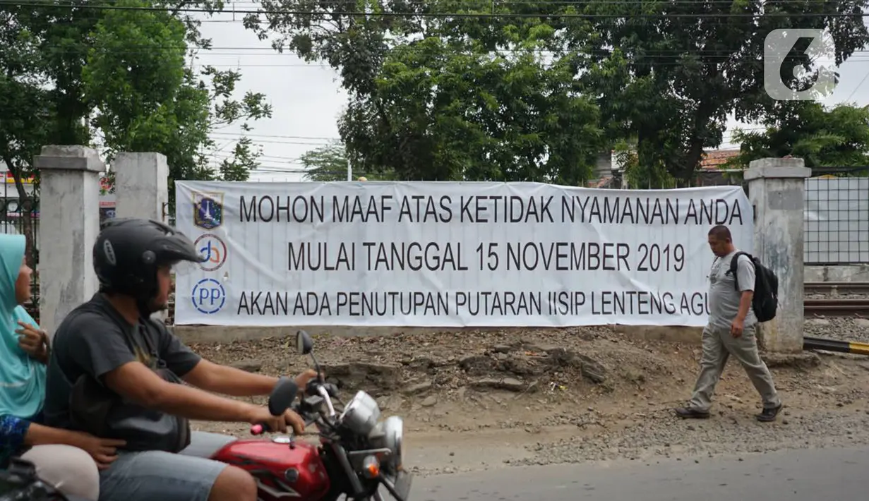 Pengendara motor dan pejalan kaki melintasi spanduk pemberitahuan di merupakan jalur putar balik kawasan Lenteng Agung, Jakarta, Kamis (14/11/2019). Mulai 15 November 2019, jalur putar balik tersebut akan ditutup terkait pembangunan flyover yang saat ini telah mulai dikerjakan. (Liputan6.com/Immanue