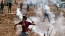 Pengunjuk rasa Palestina menggunakan katapel untuk melemparkan kembali granat gas air mata ke pasukan keamanan Israel saat demonstrasi menentang pembangunan pos terdepan Israel di desa Palestina, Ramallah, Tepi Barat, Kamis (17/10/2019). (JAAFAR ASHTIYEH/AFP)