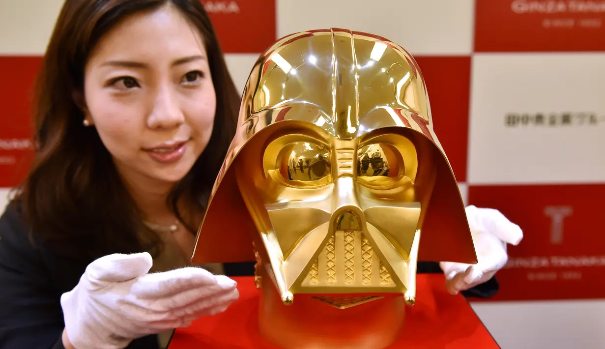 Seorang pegawai toko Tanaka Kikinzoku Jewelry memperlihatkan topeng berlapis emas murni Darth Vader, salah satu tokoh jahat di film Star Wars, di toko utama mereka di distrik perbelanjaan Ginza, Tokyo, Jepang, Selasa (25/4). (AFP Photo/Kazuhiro NOGI)