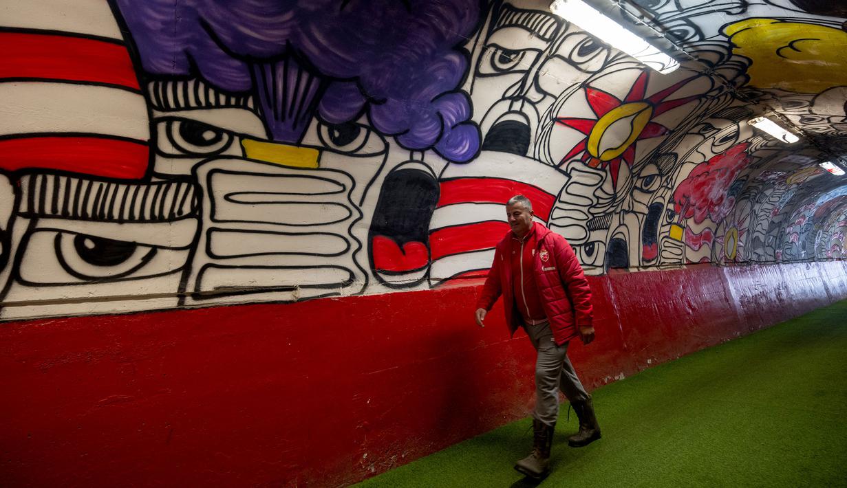 Seorang petugas melewati pintu masuk terowongan terkenal Stadion Rajko Mitic, Beograd, Serbia yang penuh mural dua hari sebelum pertandingan sepak bola Grup G Liga Champions UEFA antara Crvena Zvezda (Red Star Belgrade) dan Manchester City pada 11 Desember 2023 waktu setempat. (AFP/Andrej Isakovic)