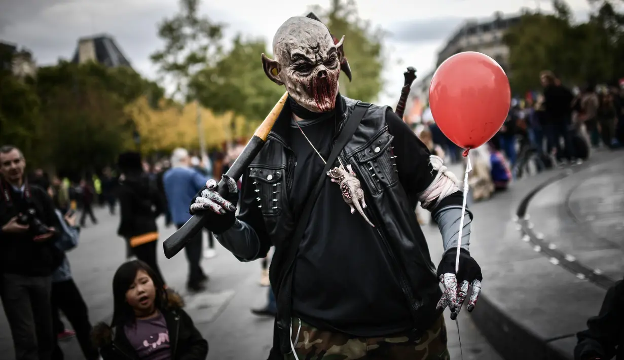 Penggemar film horor menggunakan riasan zombie saat mengikuti acara Zombie Walk di Place de la Republique, Paris, Sabtu (12/10/2019). Sejak 2008, acara Zombie Walk digelar untuk orang-orang yang terobsesi dengan mayat hidup. (Martin BUREAU / AFP)