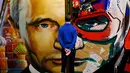 Seorang pria melihat sebuah lukisan yang menggambarkan Presiden Rusia Vladimir Putin dalam pameran Superputin di Museum Umam, Moskow (6/12). (AFP Photo/Yuri Kadobnov)