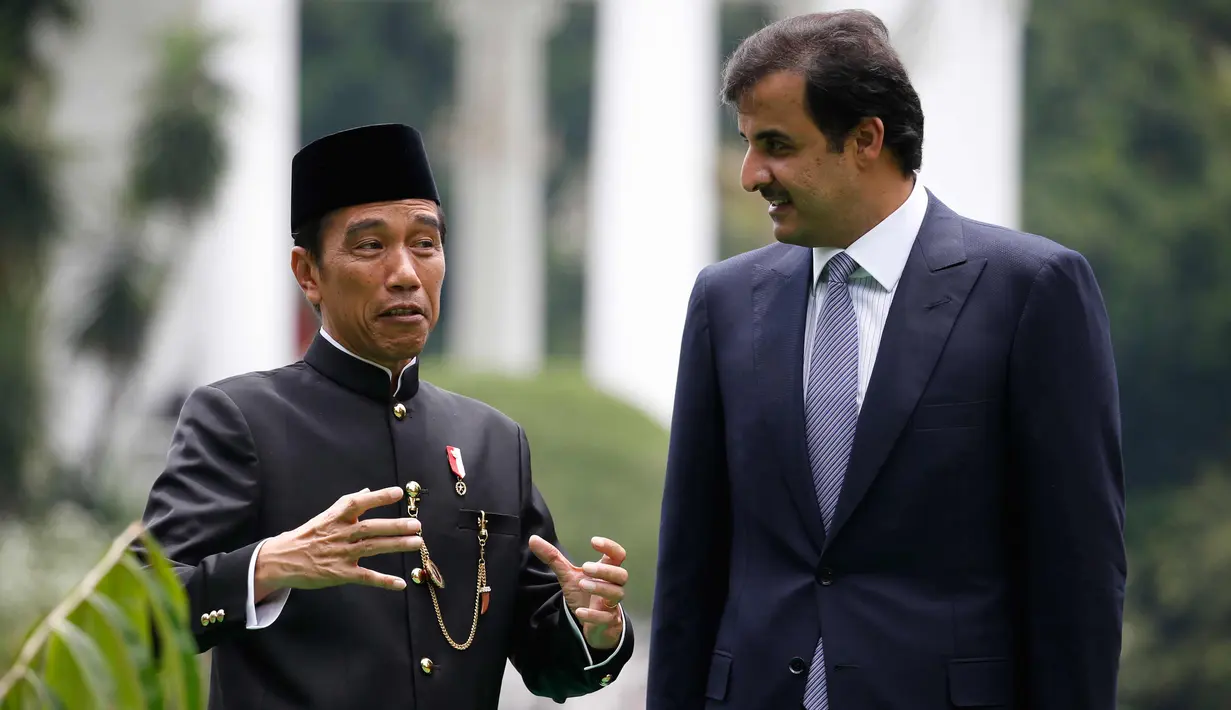 Presiden Joko Widodo (kiri) berbincang dengan Emir Qatar Syekh Tamim bin Hamad Al Thani sebelum menanam pohon eboni di Istana Bogor, Jawa Barat, Rabu (18/10). Usai penanaman pohon, keduanya melakukan pertemuan bilateral. (Beawiharta/Pool photo via AP)