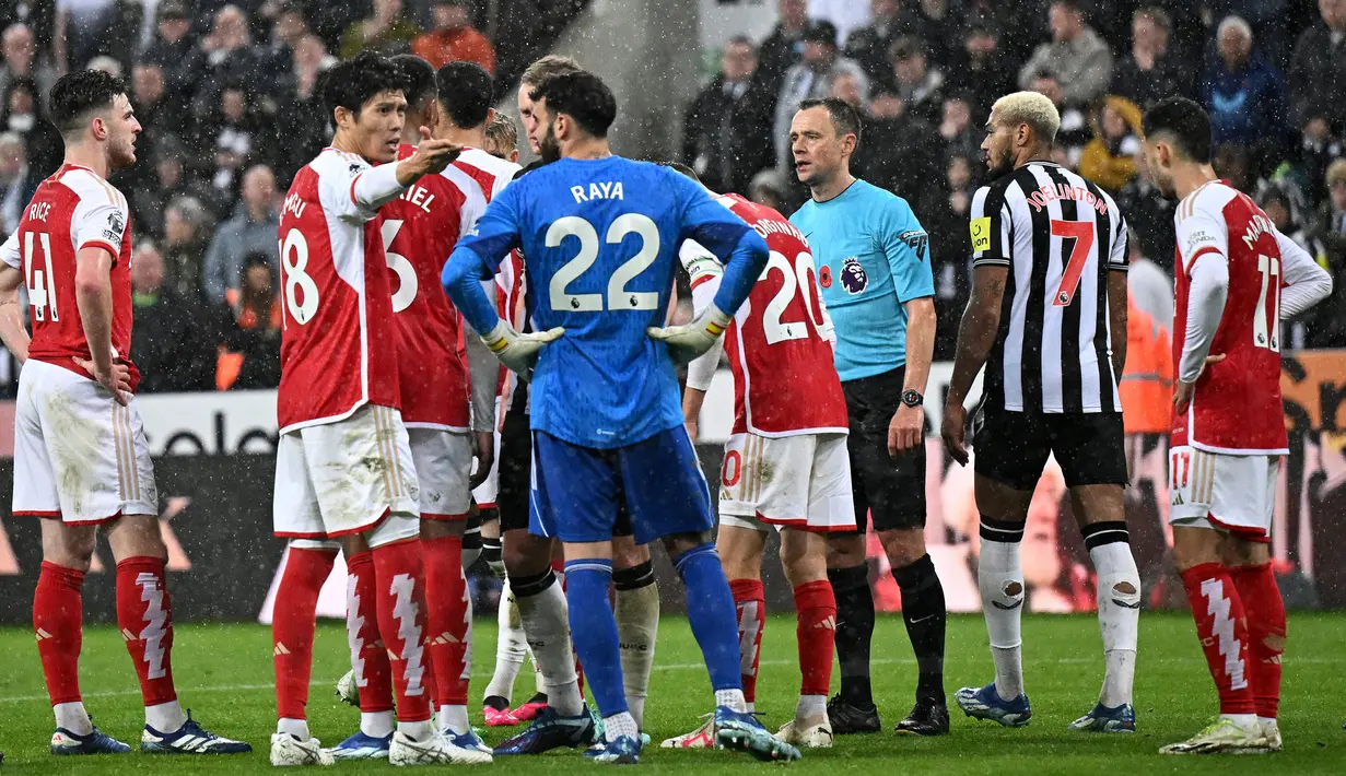 Wasit Stuart Attwell dan sejumlah pemain Arsenal dan Newcastle menunggu hasil VAR (Video Assistant Referee) pada laga lanjutan Liga Inggris 2023/2024 yang berlangsung di Stadion St. James' Park, Newcastle, Inggris, Minggu (05/11/2023) WIB. Gol kontroversial tersebut tetap disahkan oleh wasit meski telah meninjau VAR. (AFP/Oli Scarff)
