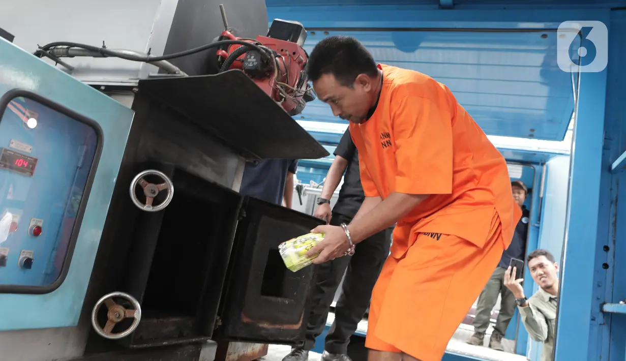 Tersangka memasukkan barang bukti narkoba jenis sabu ke dalam mesin pemusnah di Kantor BNN, Cawang, Jakarta, Selasa (4/2/2020). BNN memusnahkan sabu seberat 51,79 kg hasil penindakan di Medan, Sumatera Utara serta menangkap satu tersangka berinisial Zul. (Liputan6.com/Herman Zakharia)