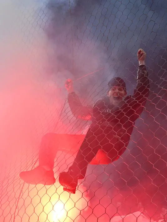 Seorang penggemar Bosnia-Herzegovina memanjat pagar saat merayakan timnya lolos ke Piala Dunia FIFA 2026 setelah memenangkan pertandingan final kualifikasi Eropa melawan Italia di stadion Bilino-Polje di Zenica pada 31 Maret 2026. (Elvis BARUKCIC/AFP)