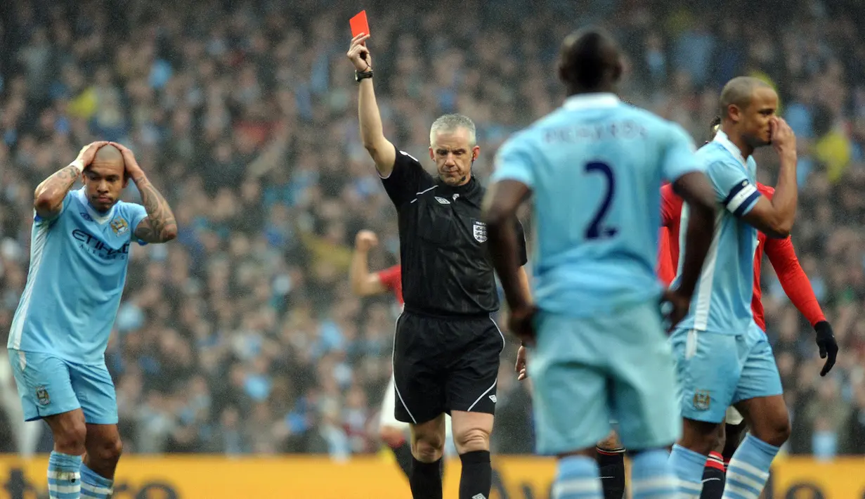 Pemain Manchester City, Vincent Kompany mendapatkan kartu merah dari wasit Chris Foy setelah melakukan tekel kepada pemain Manchester United, Nani pada laga putaran ketiga Piala FA 2011/2012 yang berlangsung di Etihad Stadium, Manchester, 8 Januari 2012. Setan Merah menang dengan skor 3-2. (AFP/Paul Ellis)