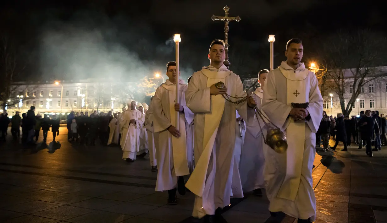 Pendeta dan umat Kristiani Lituania mengikuti prosesi Misa Natal di Katedral-Basilika di Vilnius, Lituania (24/12). (AP Photo / Mindaugas Kulbis)