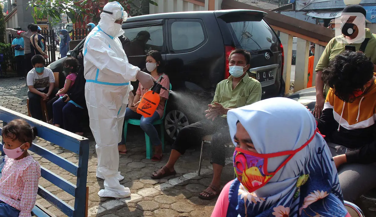 Petugas menyemprotkan disinfektan kepada warga yang akan mengikuti tes swab antigen di Polsek Pamulang, Tangerang Selatan, Rabu (19/5/2021). Swab antigen gratis itu bagi warga Pamulang yang sudah kembali usai menjalani perjalanan mudik untuk antisipasi penularan COVID-19. (merdeka.com/Arie Basuki)