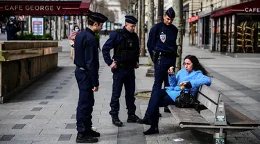 Polisi memeriksa seorang wanita saat lockdown di Jalan Champs-Elysees, Paris, Prancis, Selasa (17/3/2020). Polisi merazia warga yang masih berkeliaran di luar rumah saat Prancis memberlakukan lockdown akibat virus corona COVID-19. (MARTIN BUREAU/AFP)