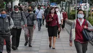 Sejumlah orang berjalan di trotoar pada saat jam pulang kantor di Kawasan Sudirman, Jakarta, Senin (8/6/2020). Aktivitas perkantoran dimulai kembali pada pekan kedua penerapan Pembatasan Sosial Berskala Besar (PSBB) transisi pandemi COVID-19. (Liputan6.com/Johan Tallo)
