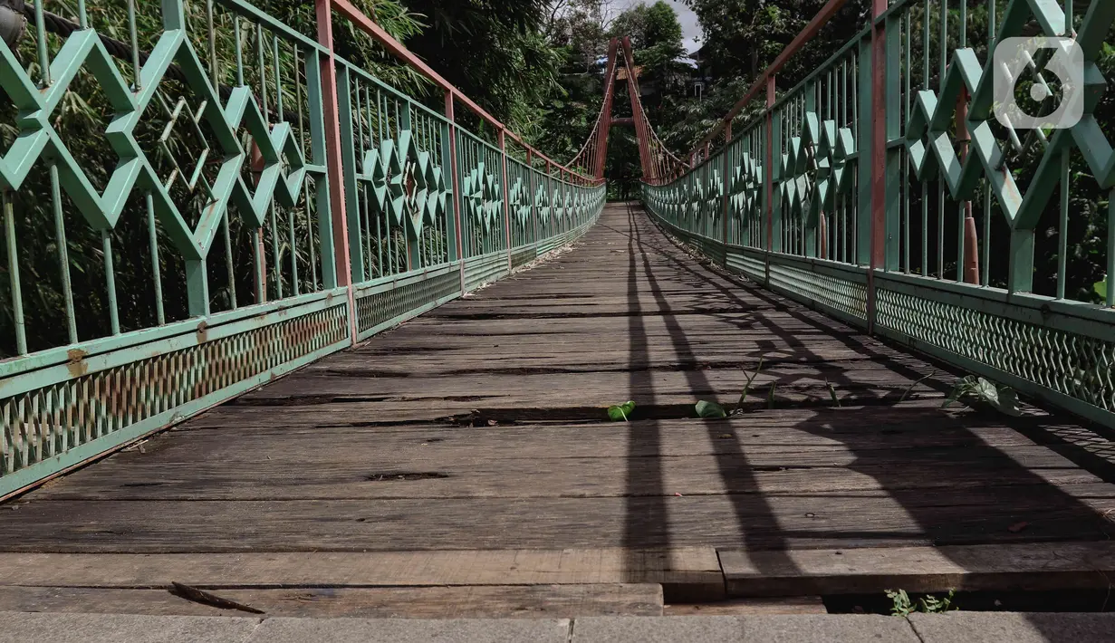Kondisi jembatan yang berlubang di Jembatan Wiratman, Srengseng Sawah, Jakarta, Sabtu (12/3/2022). Jembatan tersebut mengalami kerusakan pada papan pijak yang mulai berlubang serta besi yang berkarat dan dapat membahayakan warga yang melintas. (Liputan6.com/Herman Zakharia)