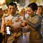 Raja Thailand Maha Vajiralongkorn dan Ratu Suthida menyapa pendukungnya di luar Grand Palace di Bangkok setelah memimpin upacara keagamaan di sebuah kuil Buddha di dalam Istana Raja pada Minggu (1/11/2020). (Lillian SUWANRUMPHA / AFP)