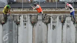 Sejumlah pekerja merapikan dinding turap yang dipasang di Kali Gendong, Penjaringan, Jakarta, Senin (10/10). Pemasangan itu untuk menguatkan dinding kali agar tidak longsor sekaligus salah satu antisipasi banjir Ibu Kota (Liputan6.com/Gempur M Surya)
