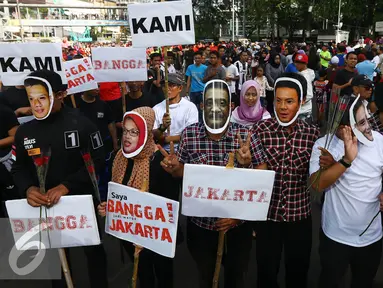 Relawan mengenakan topeng dan atribut tiga paslon Cagub/Cawagub DKI Jakarta melakukan aksi kampanye pilkada damai, aman dan sportif di CFD, kawasan Bunderan HI, Jakarta, Minggu (30/10). (Liputan6.com/Johan Tallo)