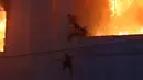 Orang-orang berusaha menyelamatkan diri di birai di sisi kasino hotel Grand Diamond City yang terbakar di Poipet pada 29 Desember 2022. Sebanyak 10 orang tewas dalam kebakaran di kasino-hotel Kamboja di perbatasan Thailand , dengan foto-foto yang menunjukkan kelompok-kelompok berkerumun mati-matian di tepian saat api yang ganas mengelilingi mereka. (AFP/STR)