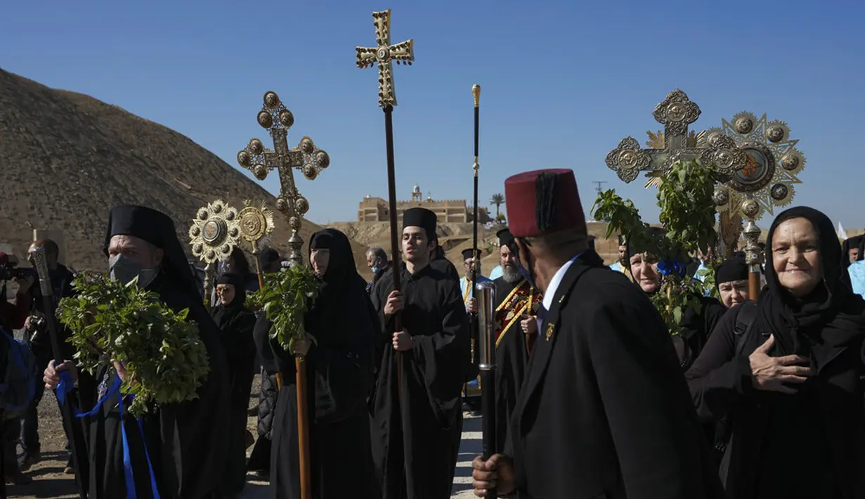 Umat Kristen Ortodoks berbaris menuju Sungai Yordan untuk berpartisipasi dalam upacara pembaptisan pada perayaan Epiphany di Qasr el Yahud, dekat kota Yerikho, Tepi Barat, 18 Januari 2022. Sungai Yordan dipercaya menjadi tempat di mana Yesus dibaptis. (AP Photo/Mahmoud Illean)