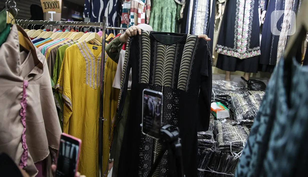 Pedagang menjualkan pakaian melalui melalui aplikasi online di Pasar Tanah Abang, Jakarta, Rabu (1/7/2020). Pedagang di Pasar Tanah Abang mulai menjual barang secara daring untuk menambah penjualan dan mengantisipasi turunnya jumlah pembeli di masa PSBB Transisi ini. (Liputan6.com/Faizal Fanani)