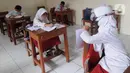 Murid kelas IV menunjukkan hasil tesnya kepada temannya yang belajar online di rumah saat kegiatan belajar tatap muka di SDN Pondok Labu 14 Pagi di Cilandak, Jakarta Selatan, Jumat (4/6/2021). (merdeka.com/Arie Basuki)