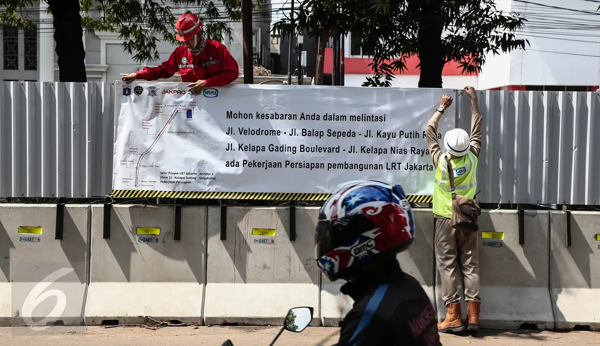 Pekerja memasang spanduk proyek Light Rail Transit (LRT) Velodrome di kawasan Rawamangun, Jakarta, (22/6). Ini merupakan proyek untuk penunjang fasilitas infrastruktur Asian Games dan ditargetkan selesai pada Februari 2018. (Liputan6.com/Faizal Fanani)