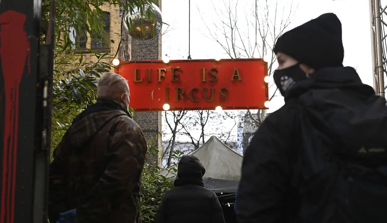 Orang-orang antre untuk melakukan tes usap (swab test) COVID-19 di luar kelab malam KitKatClub yang legendaris di Berlin, Jerman, Jumat (4/12/2020). Ditutup selama delapan bulan terakhir karena pembatasan virus corona, kelab malam itu diubah menjadi pusat pengujian Covid-19. (Tobias SCHWARZ/AFP)