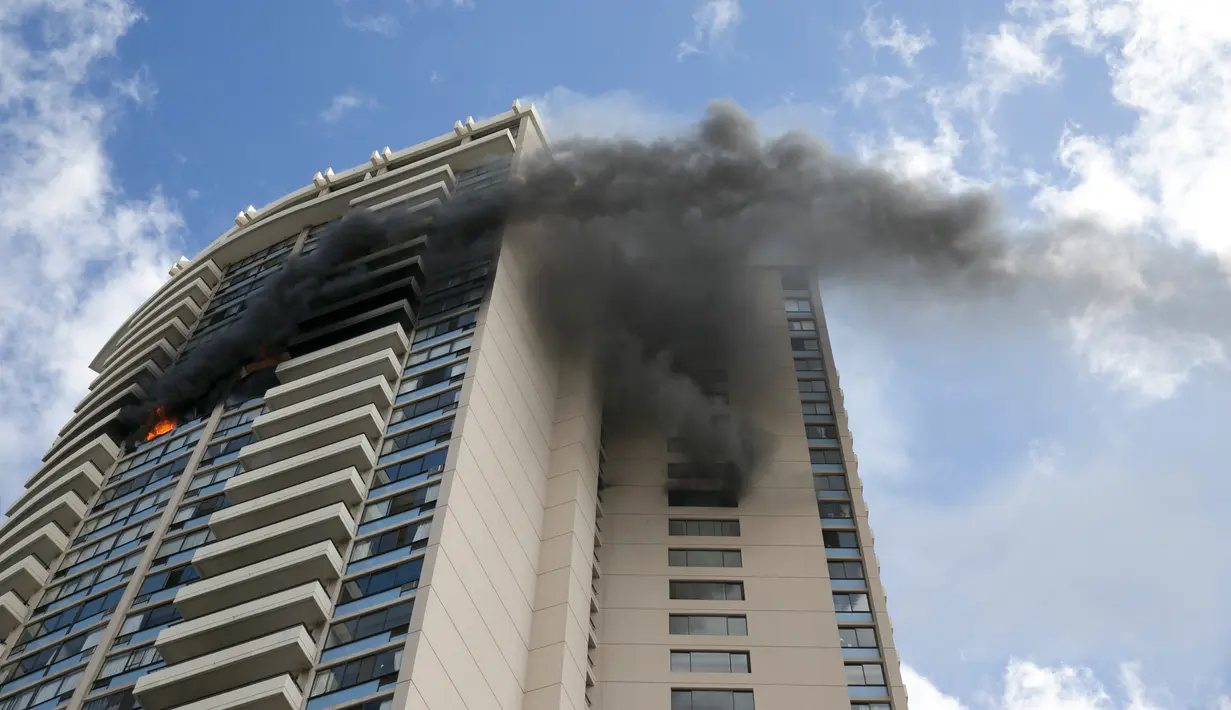Kepulan asap hitam menyelimuti bagian gedung saat terjadi kebakaran di apartemen Marco Polo, Honolulu (14/7). Menurut petugas setempat, titik api pertama kali muncul di lantai 26 hingga akhirnya menjalar ke beberapa bagian gedung. (AP Photo/Marco Garcia)