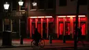 Orang-orang berjalan melewati rumah bordil di Red Light District Amsterdam, Belanda, Rabu (3/4). Pemerintah melarang tur prostitusi ke Red Light District mulai 1 Januari 2020. (REUTERS/Yves Herman)