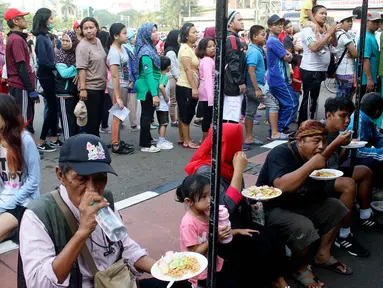 Warga memakan nasi goreng gratis ala prajurit Korps Marinir TNI AL saat car free day di Jakarta, Minggu (5/11). Kegiatan bagi-bagi nasi goreng ini dalam rangka menyambut HUT Marinir ke-72. (Liputan6.com/Angga Yuniar)