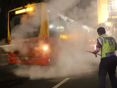 Petugas menyemprotkan apar ke TransJakarta yang mengeluarkan asap dari dalam mobil di Bundaran HI, Jakarta, Rabu (25/4) malam. TransJakarta koridor 1 tersebut mengeluarkan asap usai terdengar suara ledakan. (Liputan6.com/Angga Yuniar)