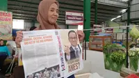 Seorang pedagang di Pasar Klojen, Kota Malang, menunjukkan sebuah tabloid&nbsp;KBA News Paper berisi profil dan klaim prestasi Anies Baswedan yang dibagikan oleh relawan pendukung Anies Baswedan pada awal September 2022. (Liputan6.com/Zainul Arifin)&nbsp;